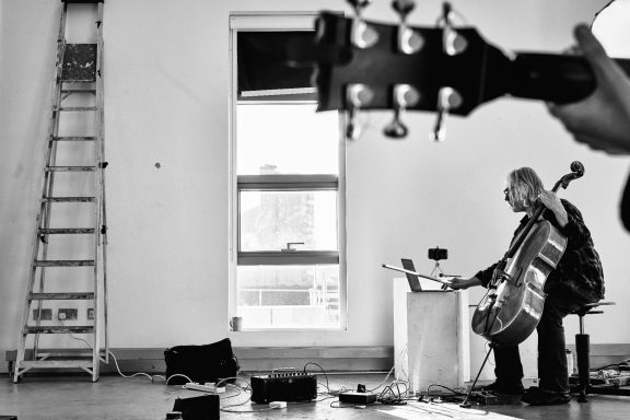 Photo: Chris Freeman Peter Nagle portrait in background with cello and guitar headstock in foreground